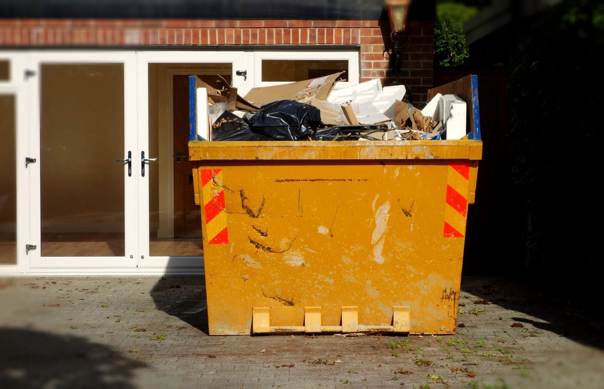 A yellow dumpster skip filled with building and household waste, created as an independent concept for a waste hauling website