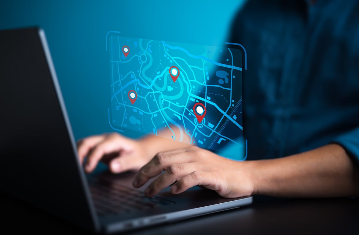 Businessman use computer laptop to pinpoint for business address on world map with location. Searching or Marking destination for travel or finding places in GPS Satellite coordinates online system.