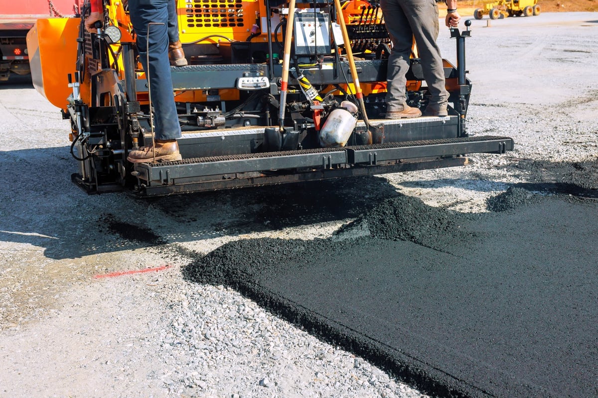 Workers operating a paving machine to lay new asphalt, created as an independent concept for a paver company website