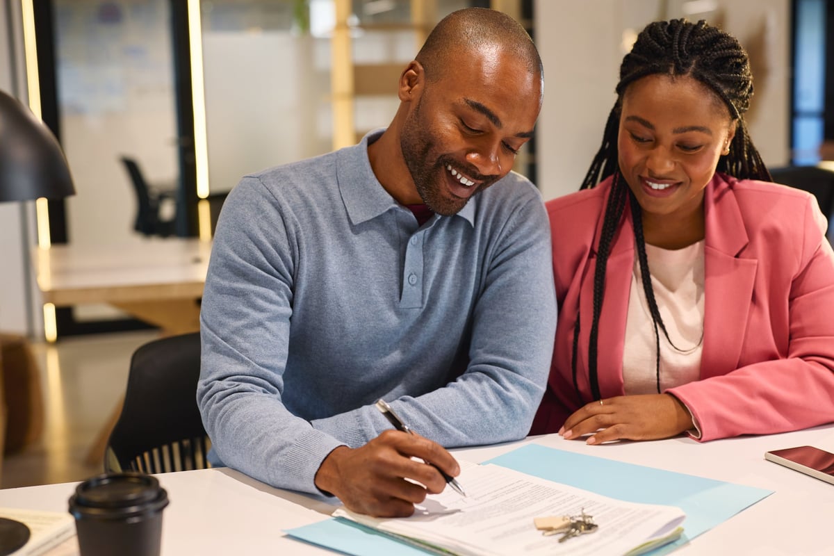 Happy couple signing a mortgage contract at an office closing on their new home, created as an independent concept for a Mortgage Company website