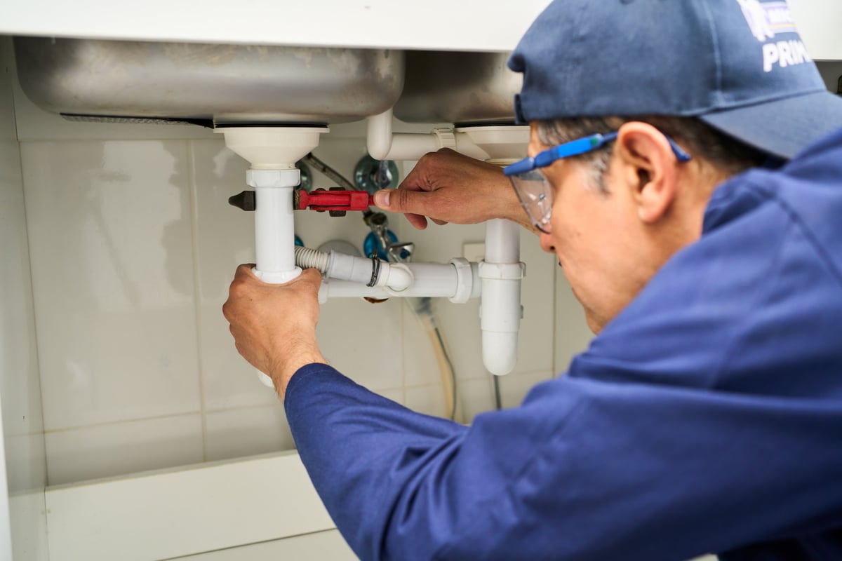 Professional plumber fixing a sink and working on pipes for Johnson and Sons Plumbing