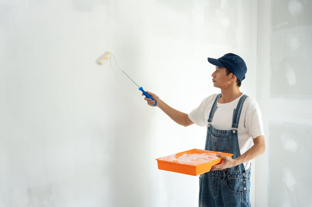 Professional house painter using a brush to paint an interior wall, created as an independent concept for a Painting Contractor website
