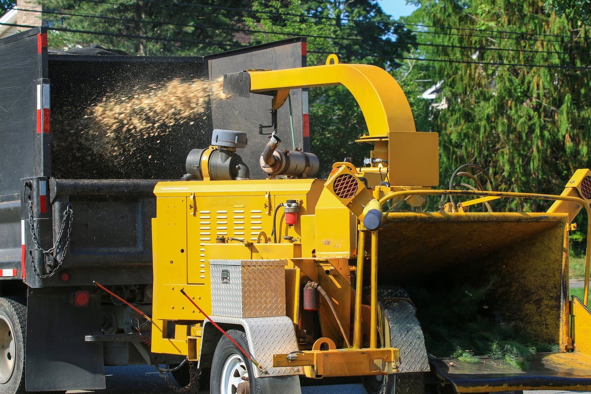 Tree service worker loading branches into a wood chipper, created as an independent concept for a Tree Service & Land Clearing website