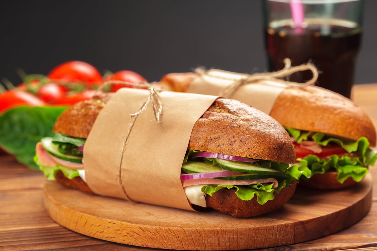 Fresh gourmet sandwiches with lettuce and tomatoes on a wooden table, created as an independent concept for a Sandwich Shop website