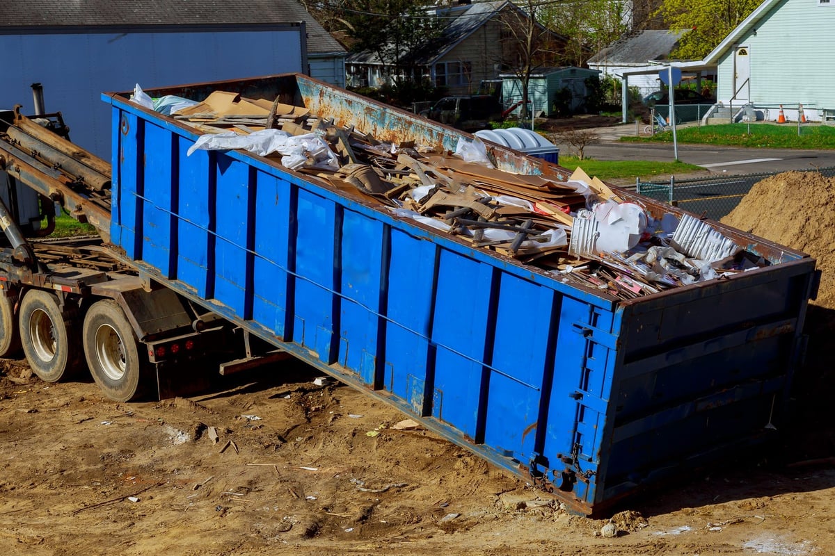 Truck loading a full skip waste management container for Johnny's Hauls junk removal and hauling service