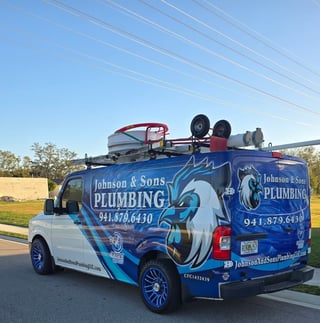 Blue and white Johnson and Sons Plumbing service van with decorative pipe graphics and contact number 941-879-6430